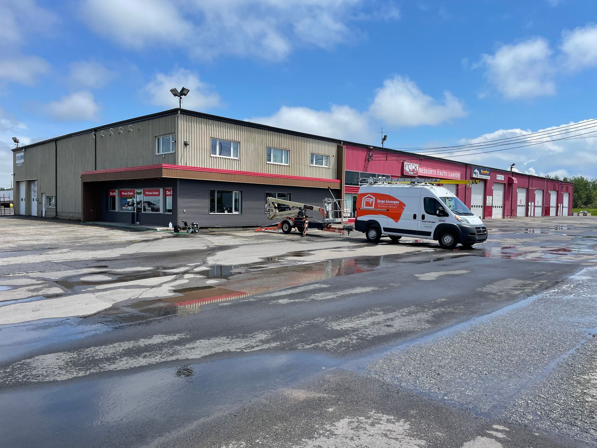 Une camionnette blanche est garée devant un grand immeuble.