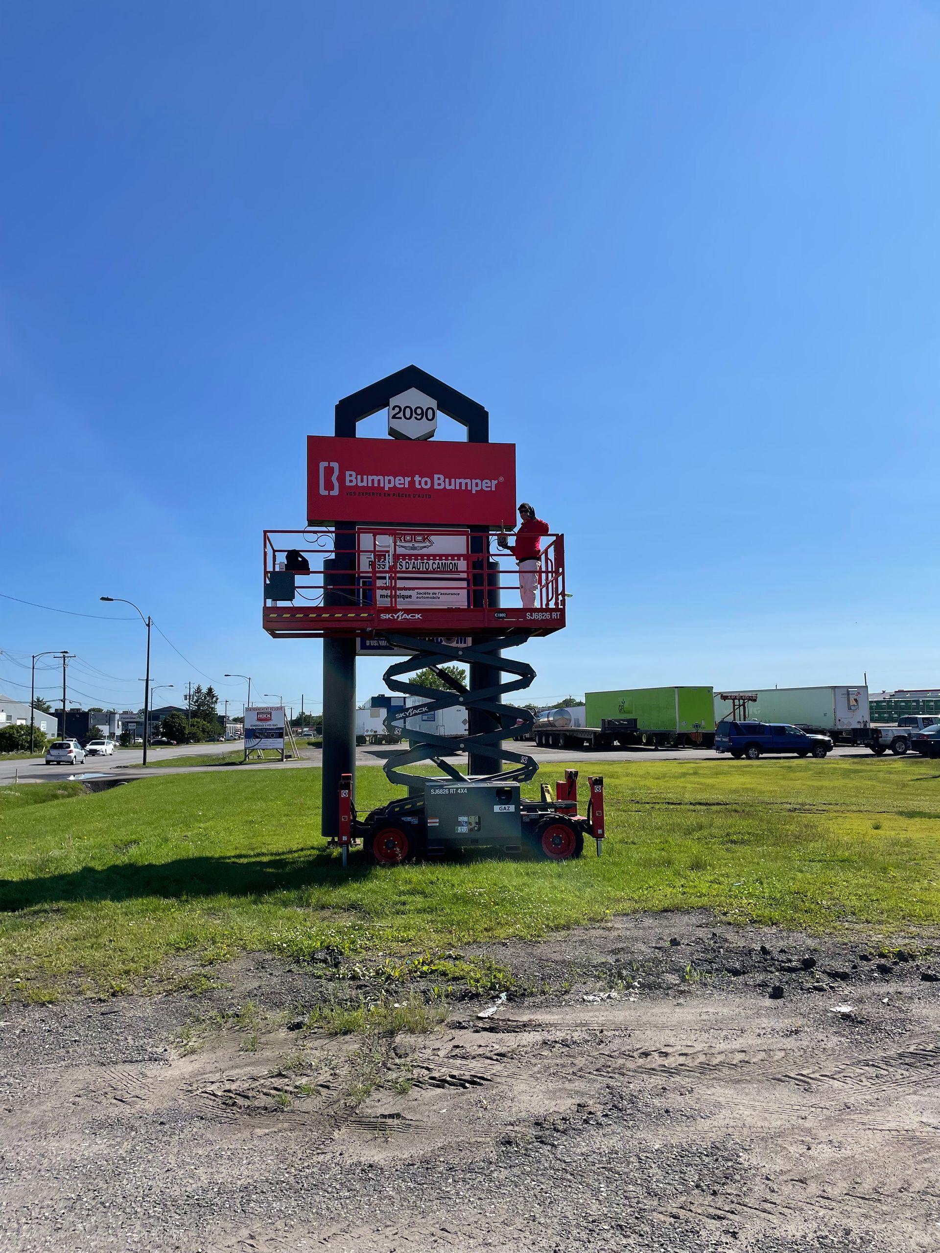 Un grand panneau rouge est en construction dans un champ herbeux.