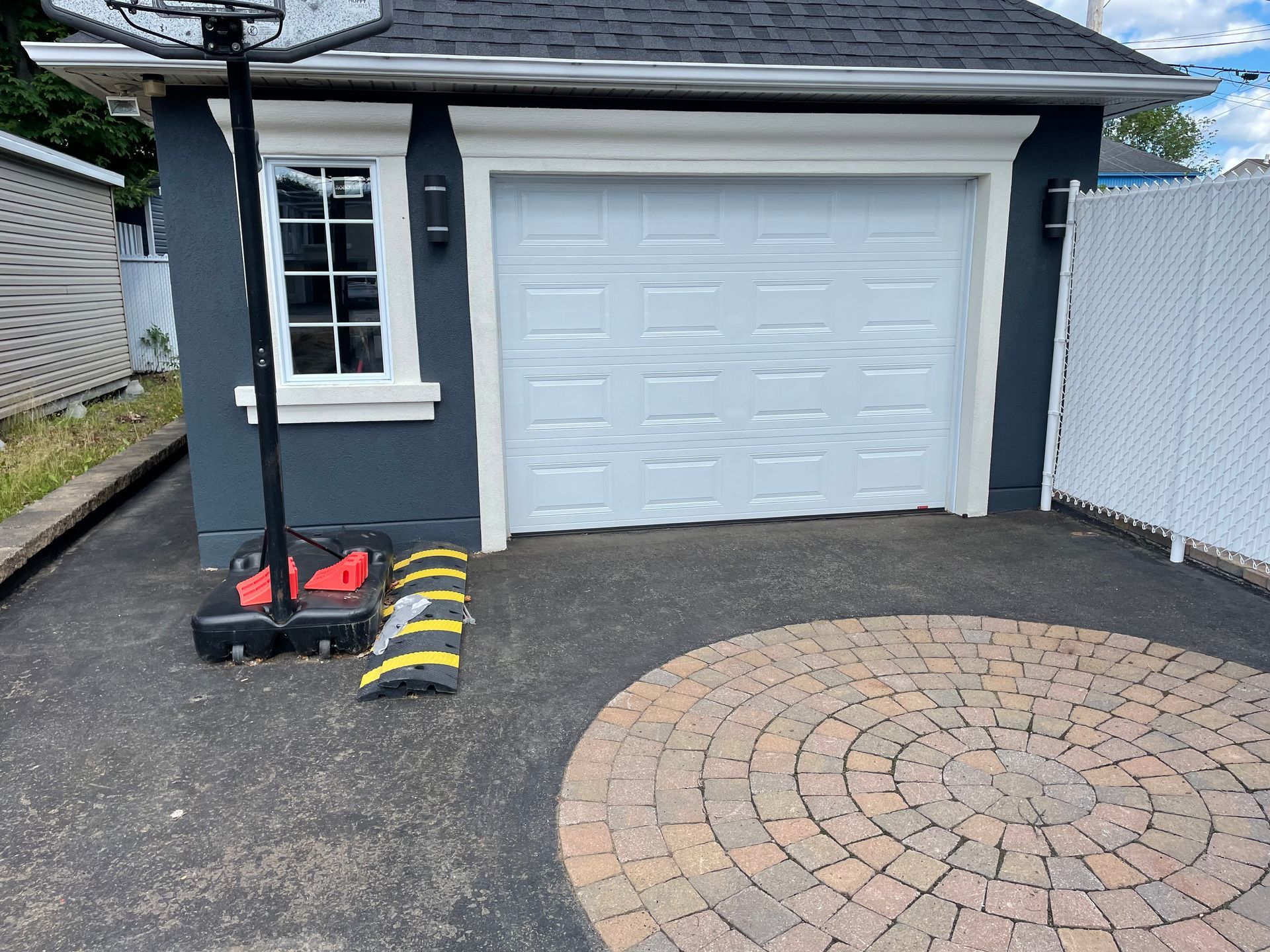 Un panier de basket est posé devant une porte de garage.