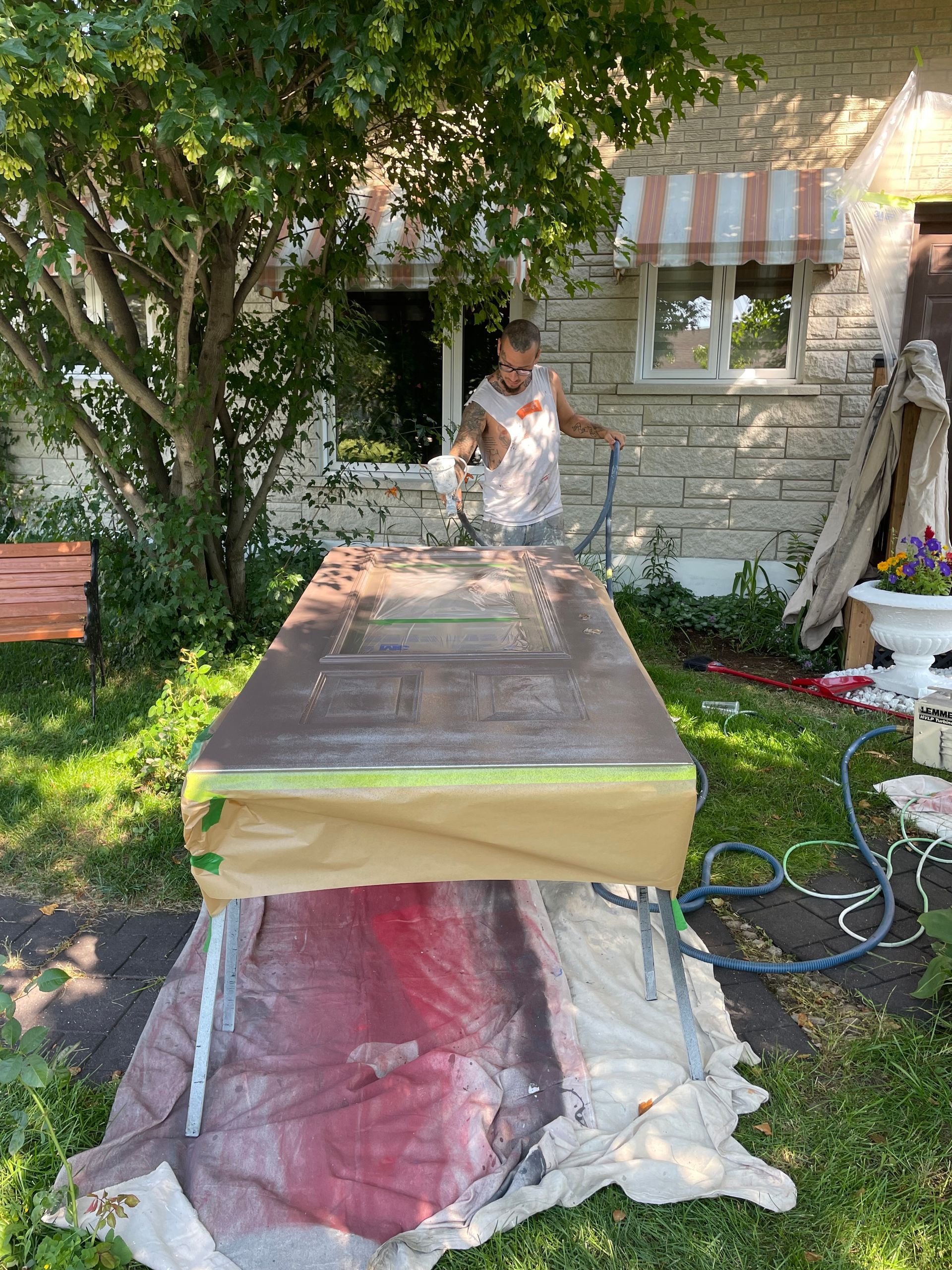 Un homme peint une porte dans la cour d'une maison.