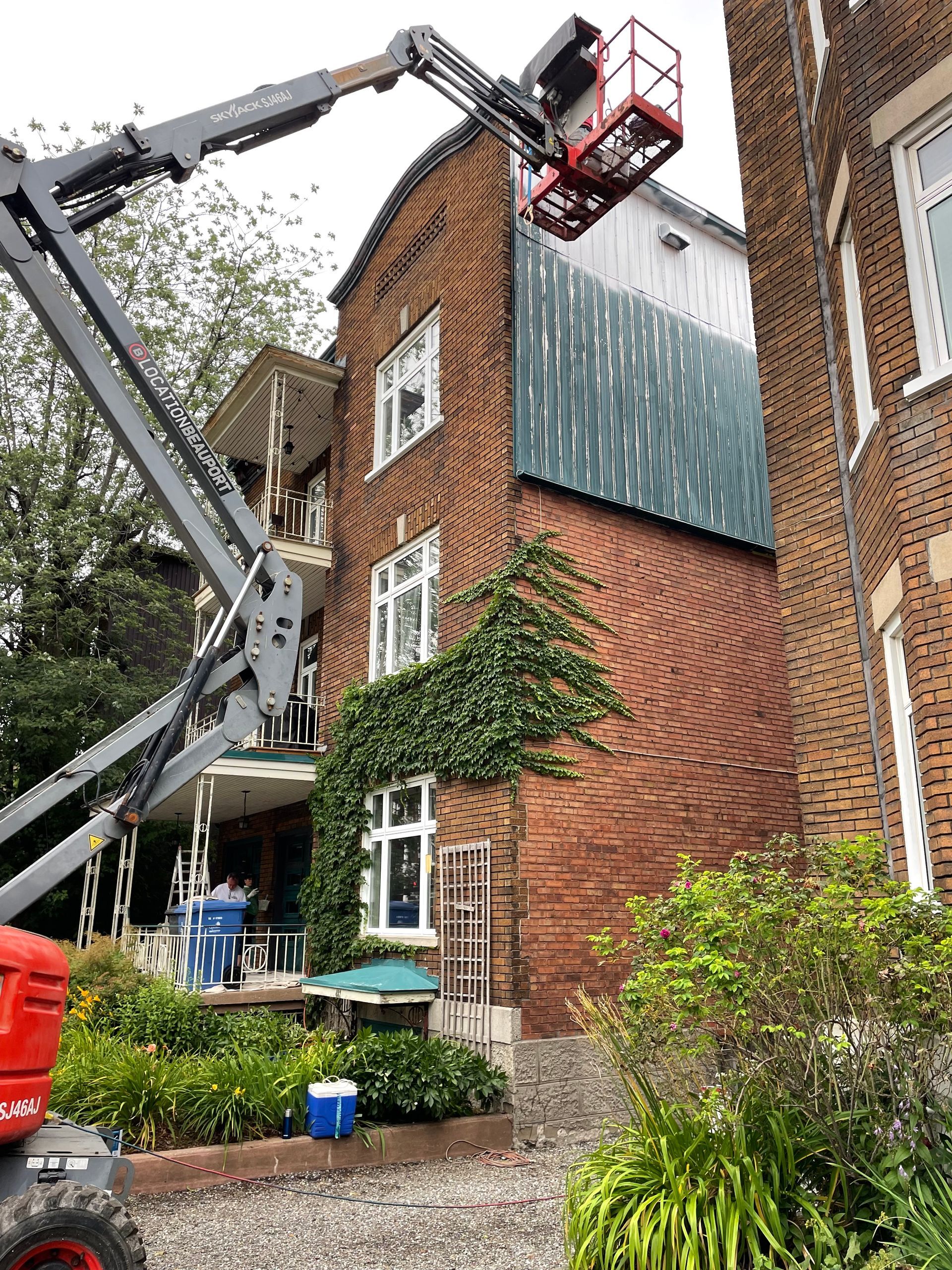 Une grue soulève un grand bâtiment en brique.