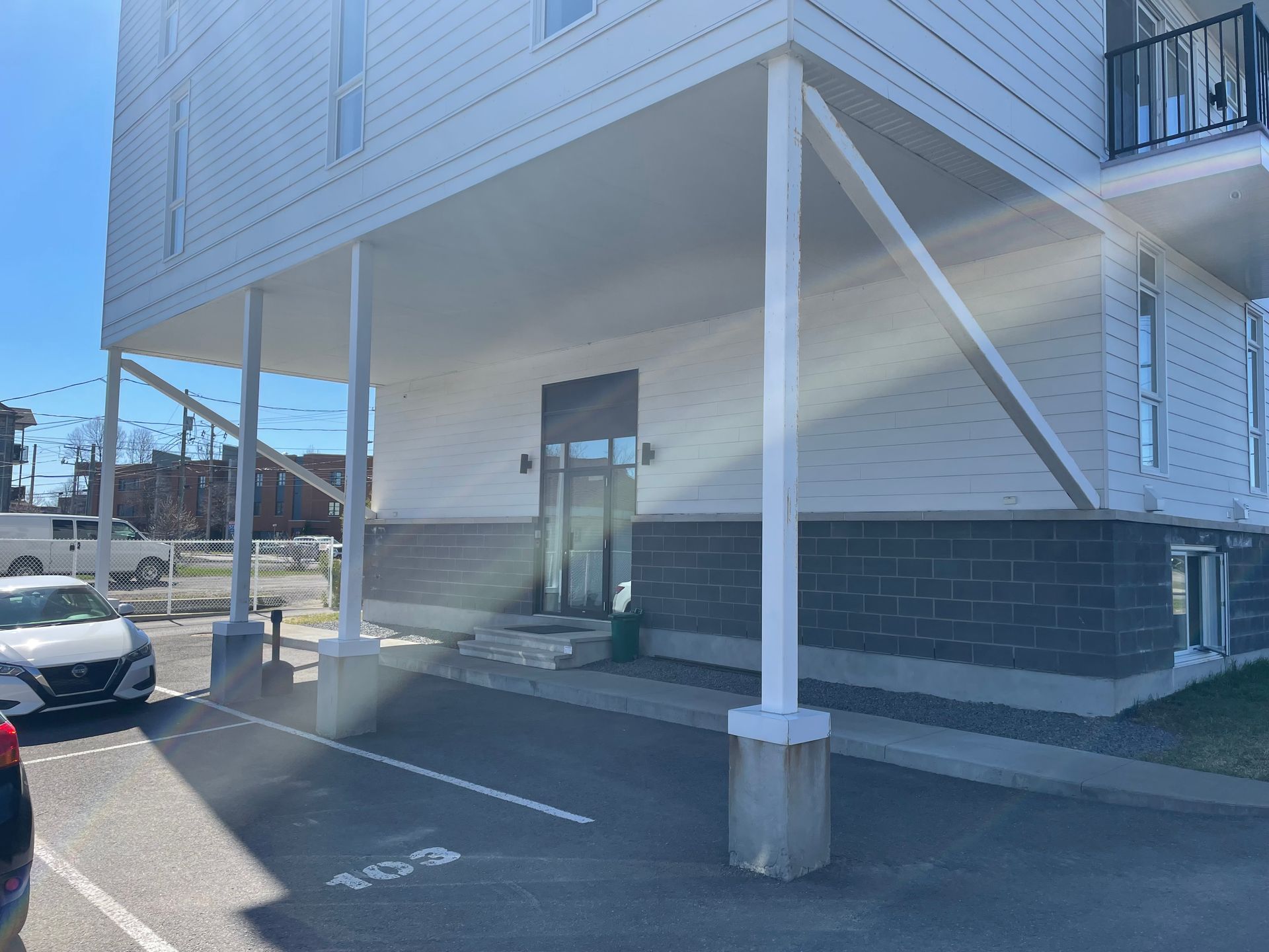 Une voiture blanche est garée devant un immeuble.