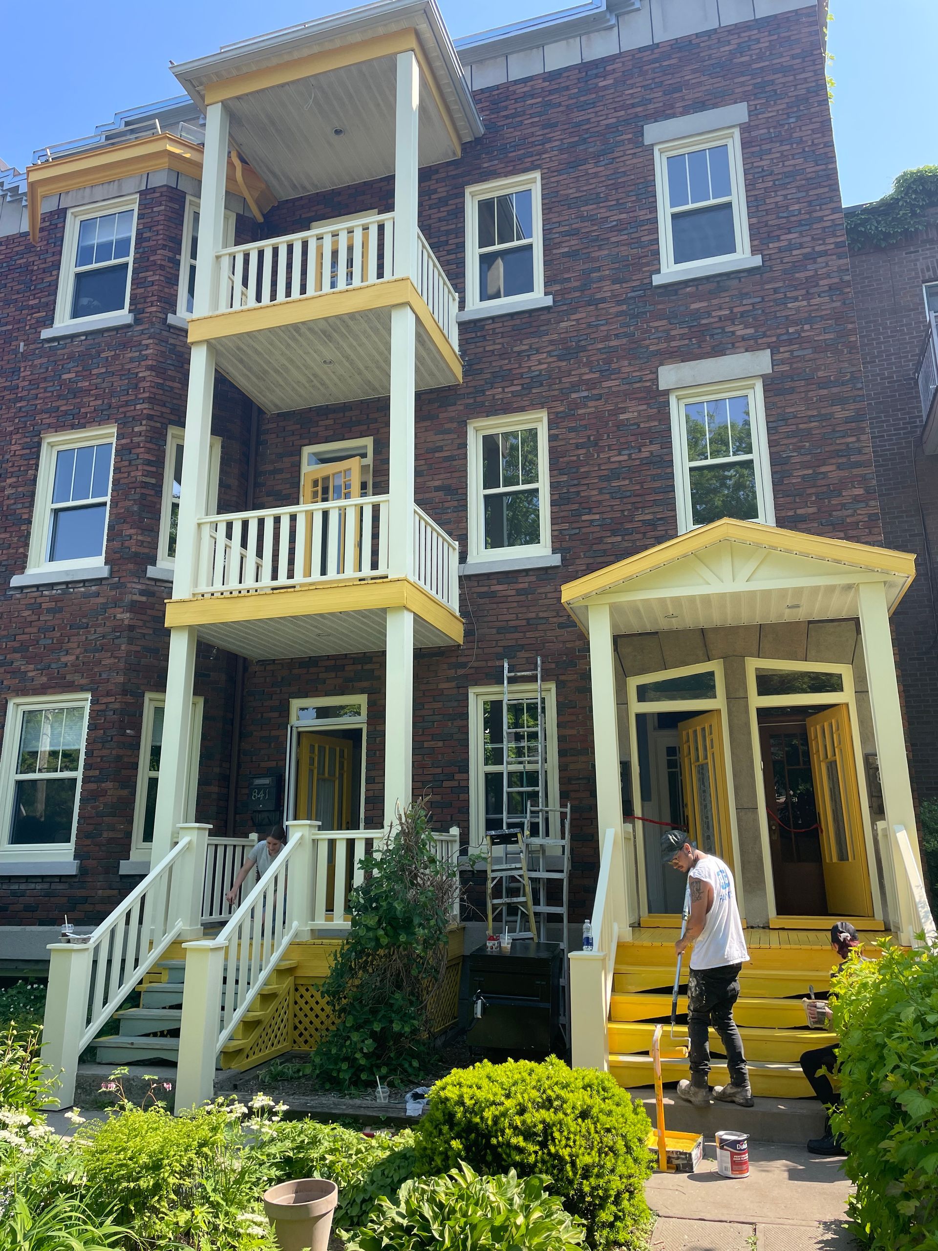 Un homme peint la façade d'un immeuble en brique