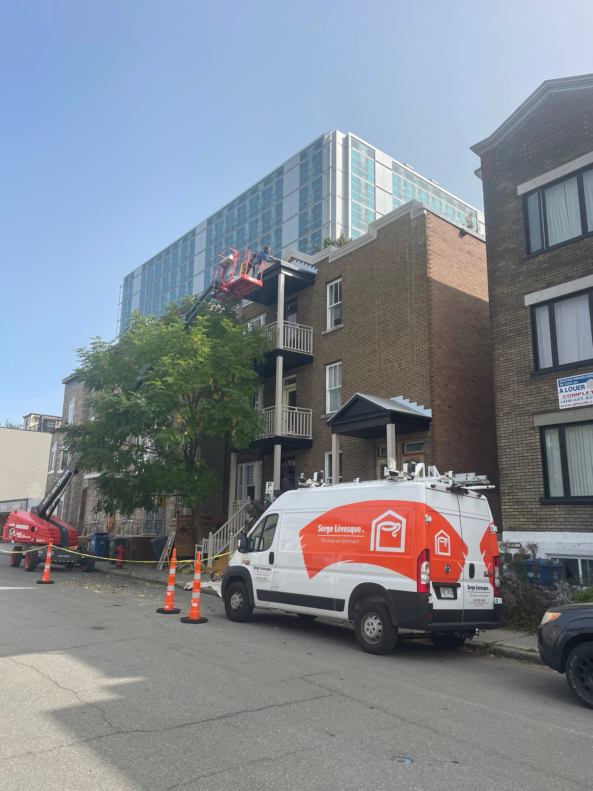 Une camionnette blanche est garée devant un immeuble