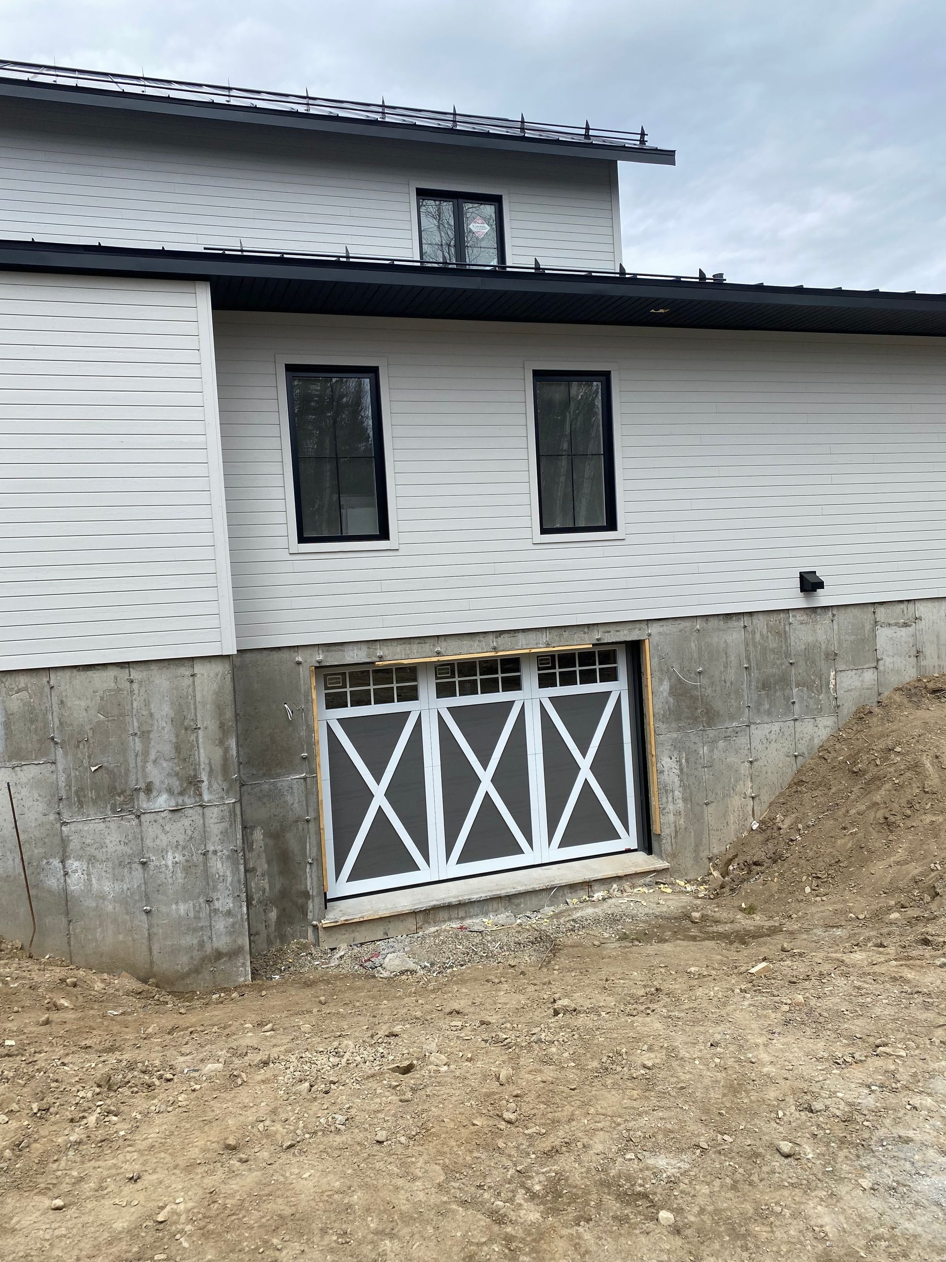 Une maison blanche avec une porte de garage et deux fenêtres.
