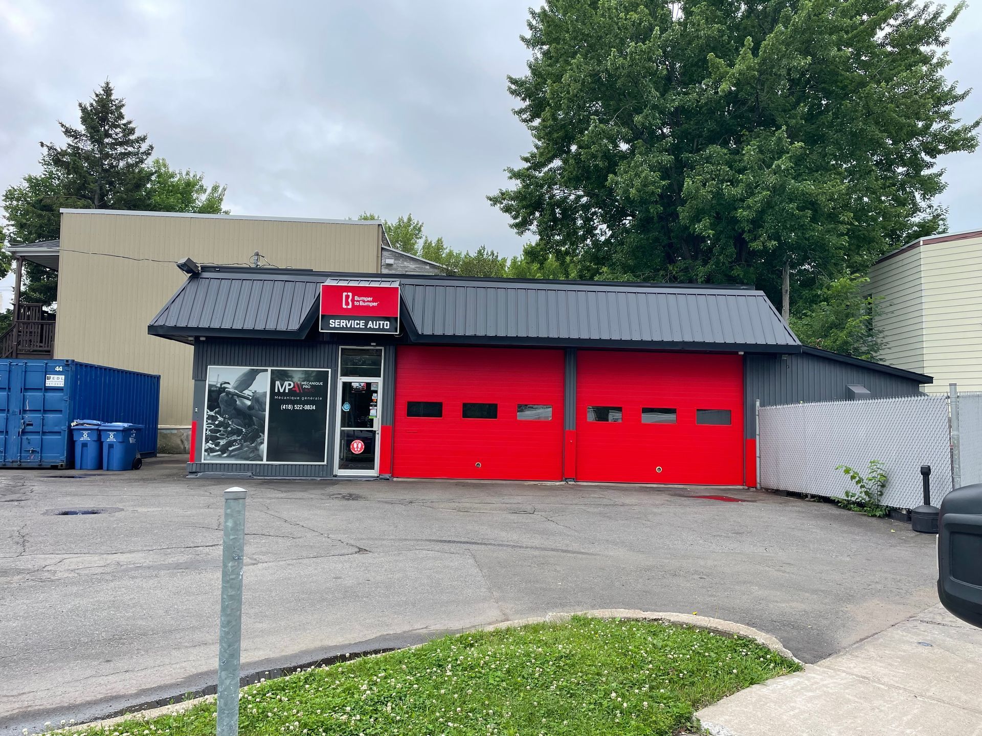 Un bâtiment avec une porte de garage rouge et un toit noir