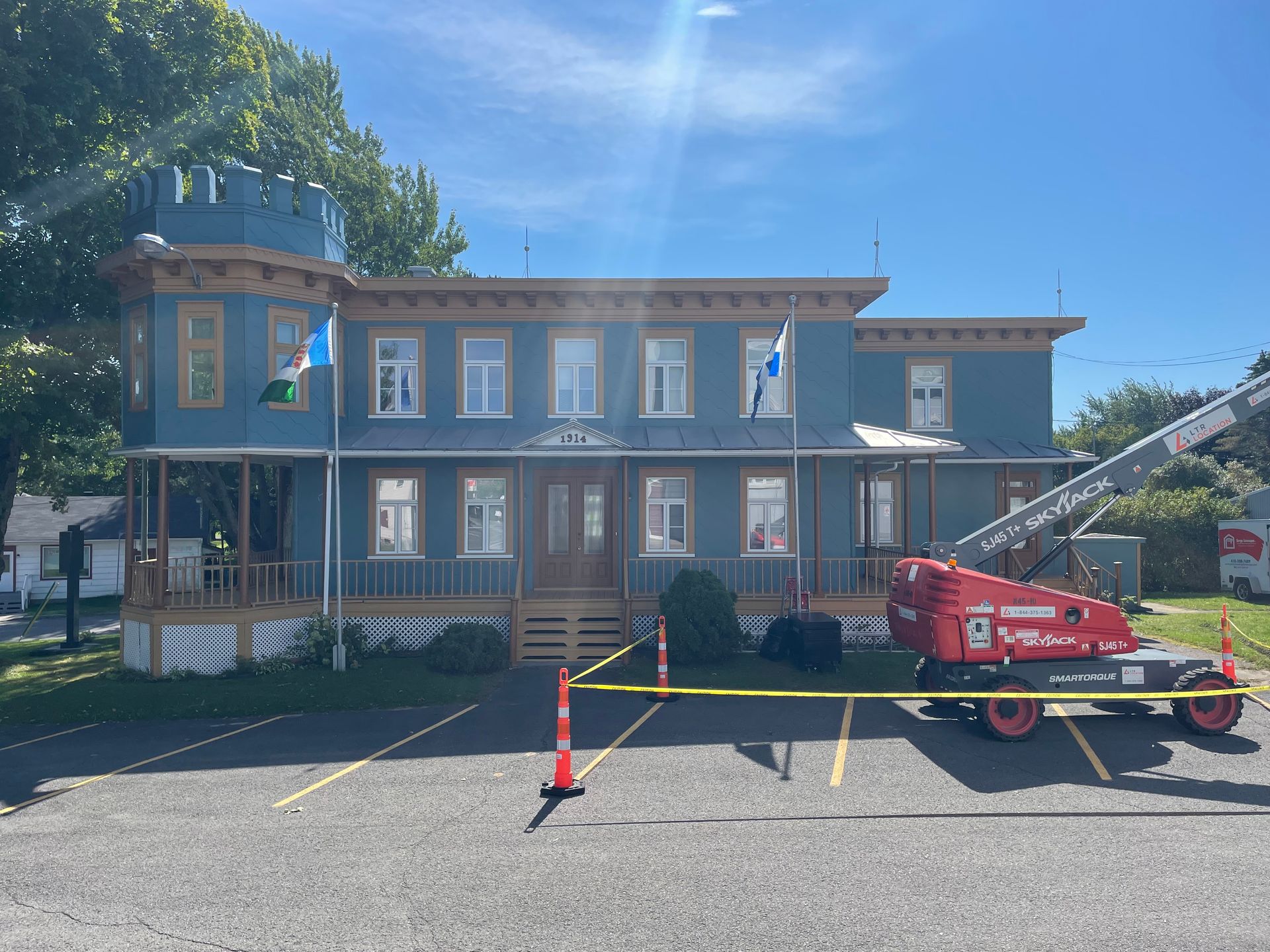 Un grand bâtiment bleu avec une grue rouge garée devant.
