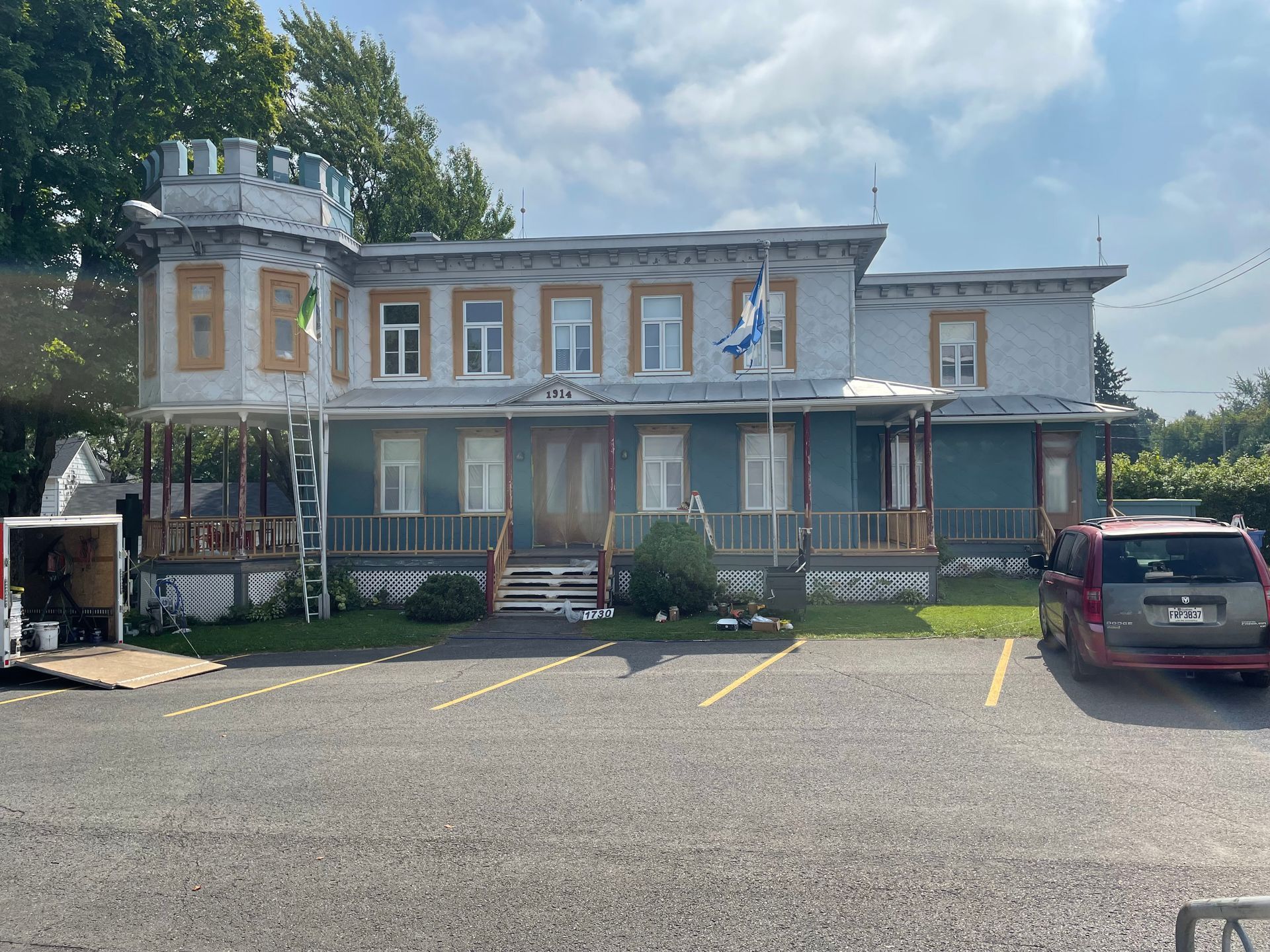 Un grand bâtiment avec une camionnette rouge garée devant.