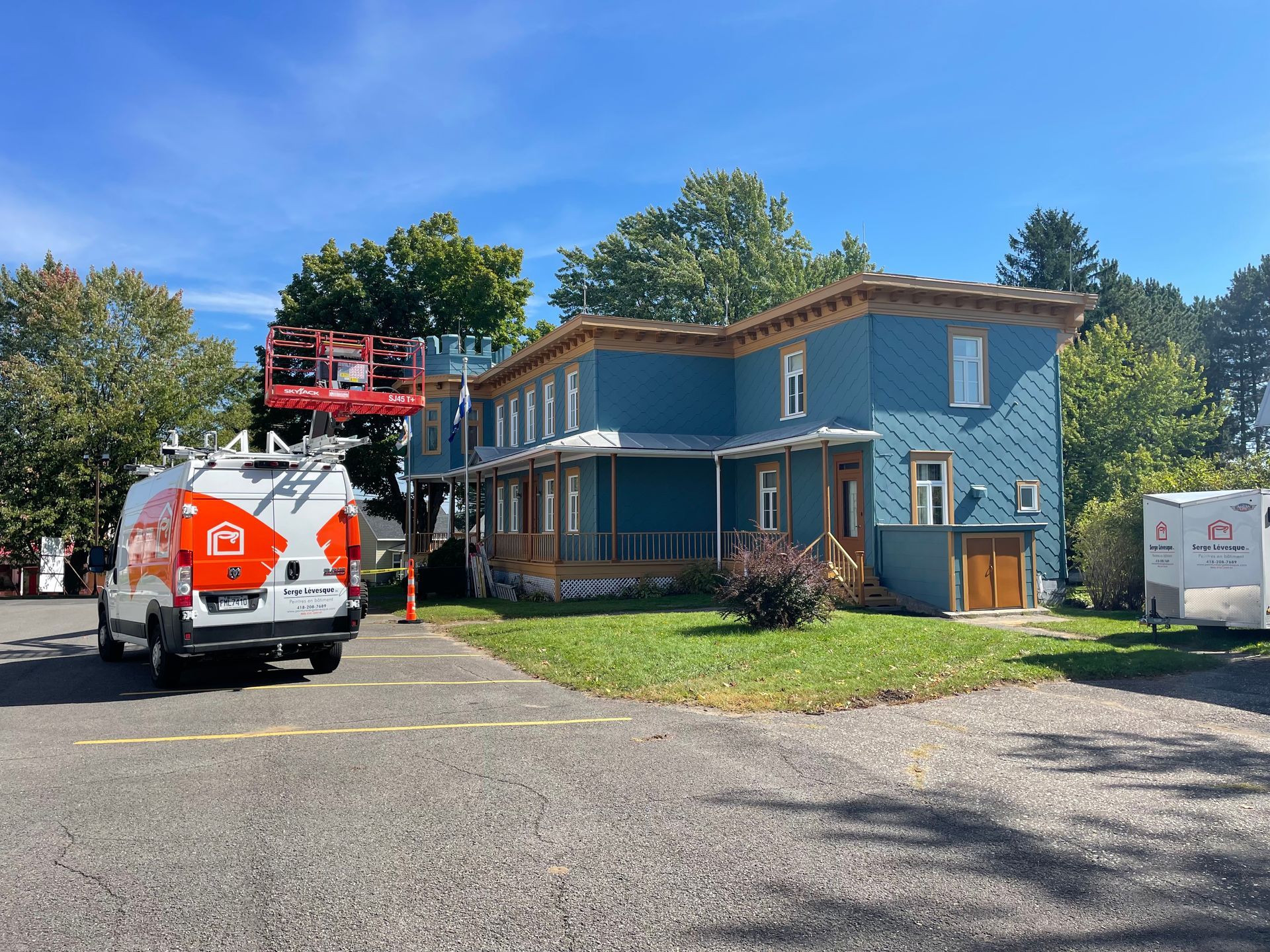 Maison bleue en rénovation avec un camion utilitaire et un élévateur devant.