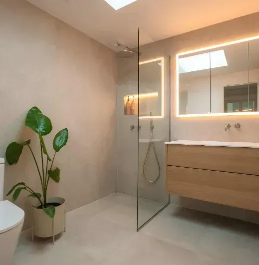 Moderne badeværelse med bruser, træhåndvask og en stor stueplante.
