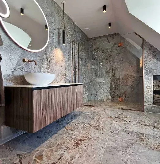 Moderne badeværelse med stenfliser på vægge og på gulvet, træbordplade, håndvask og stort spejl.