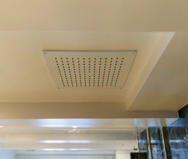 Firkantet, hvidt loftmonteret brusehoved med mange små dyser.