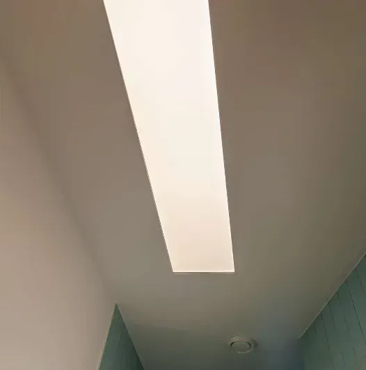 Lang, rektangulær indbygget lampe i et hvidt loft.