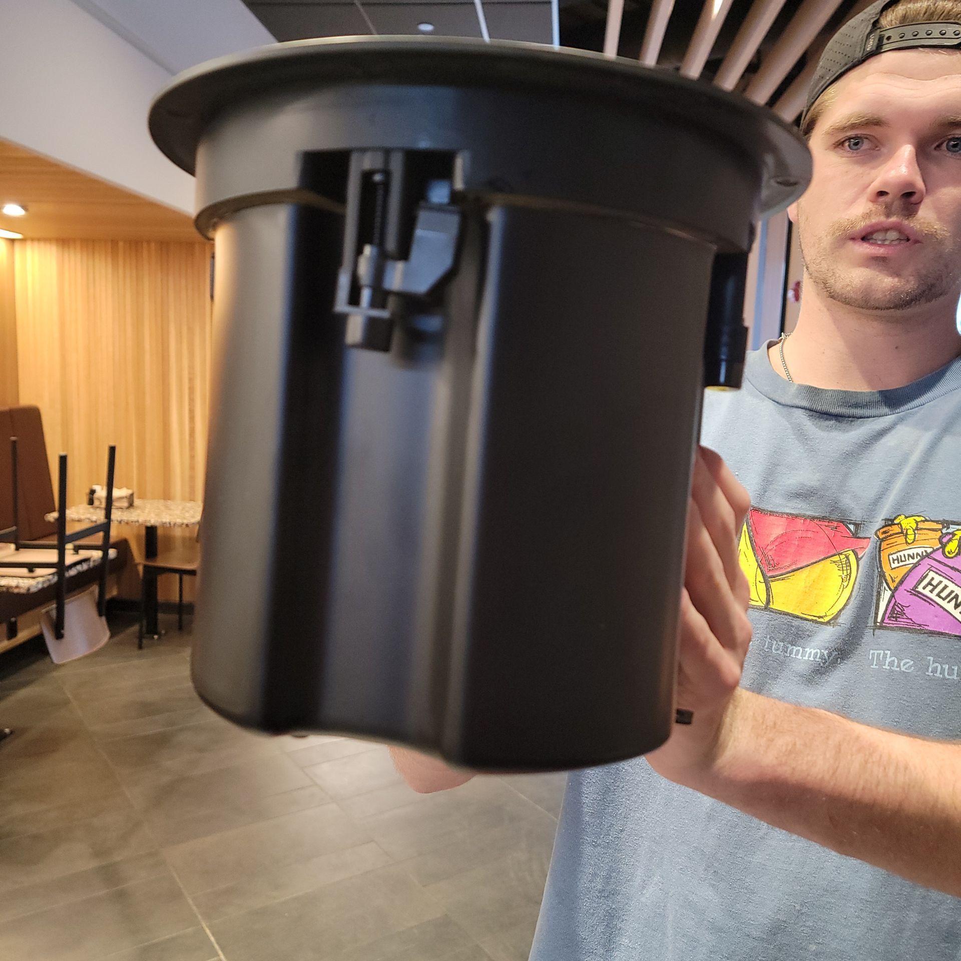 Man holding a black plastic container with a circular rim and latch.