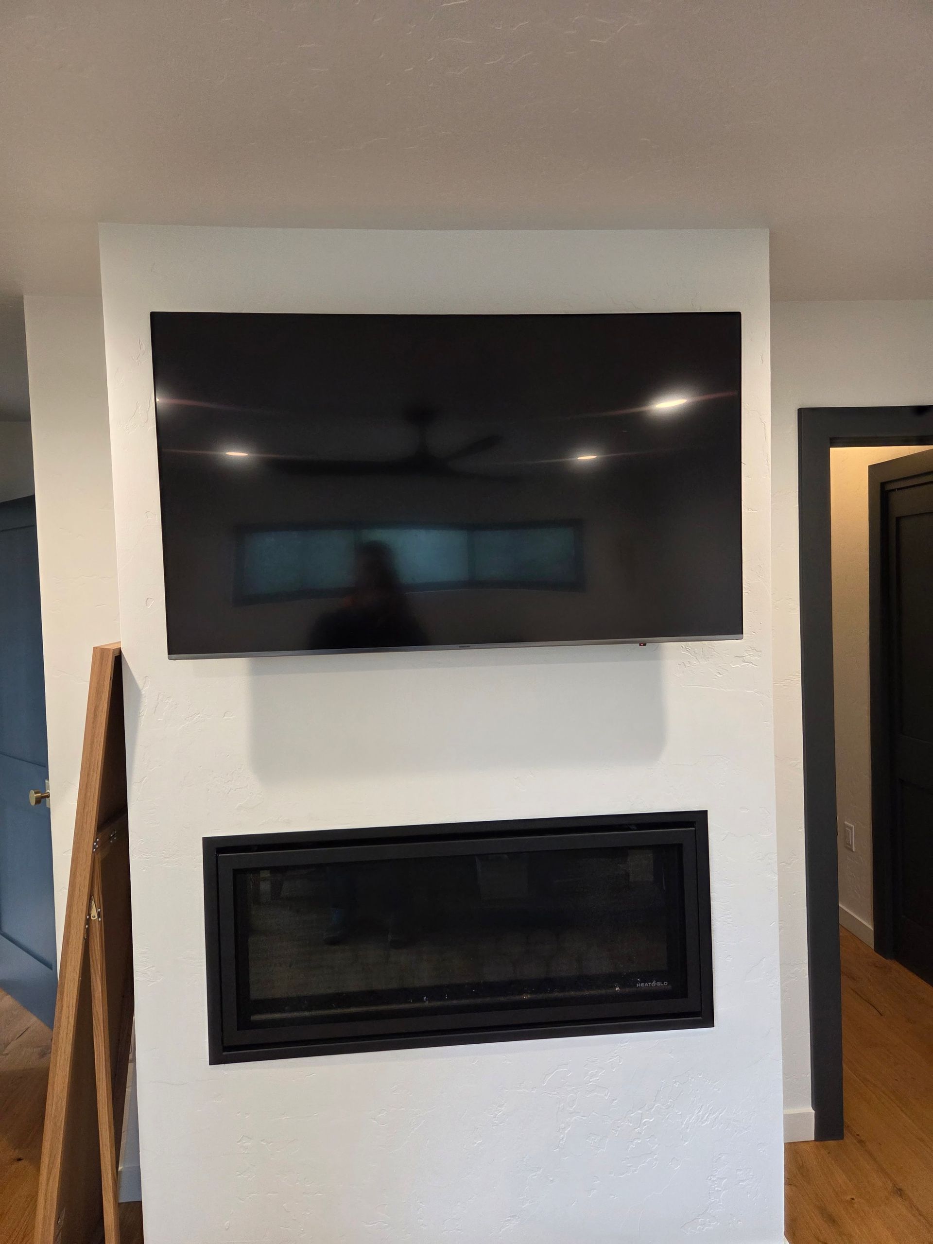 Large flat-screen TV professionally mounted above a modern linear fireplace in a Missoula, Montana home