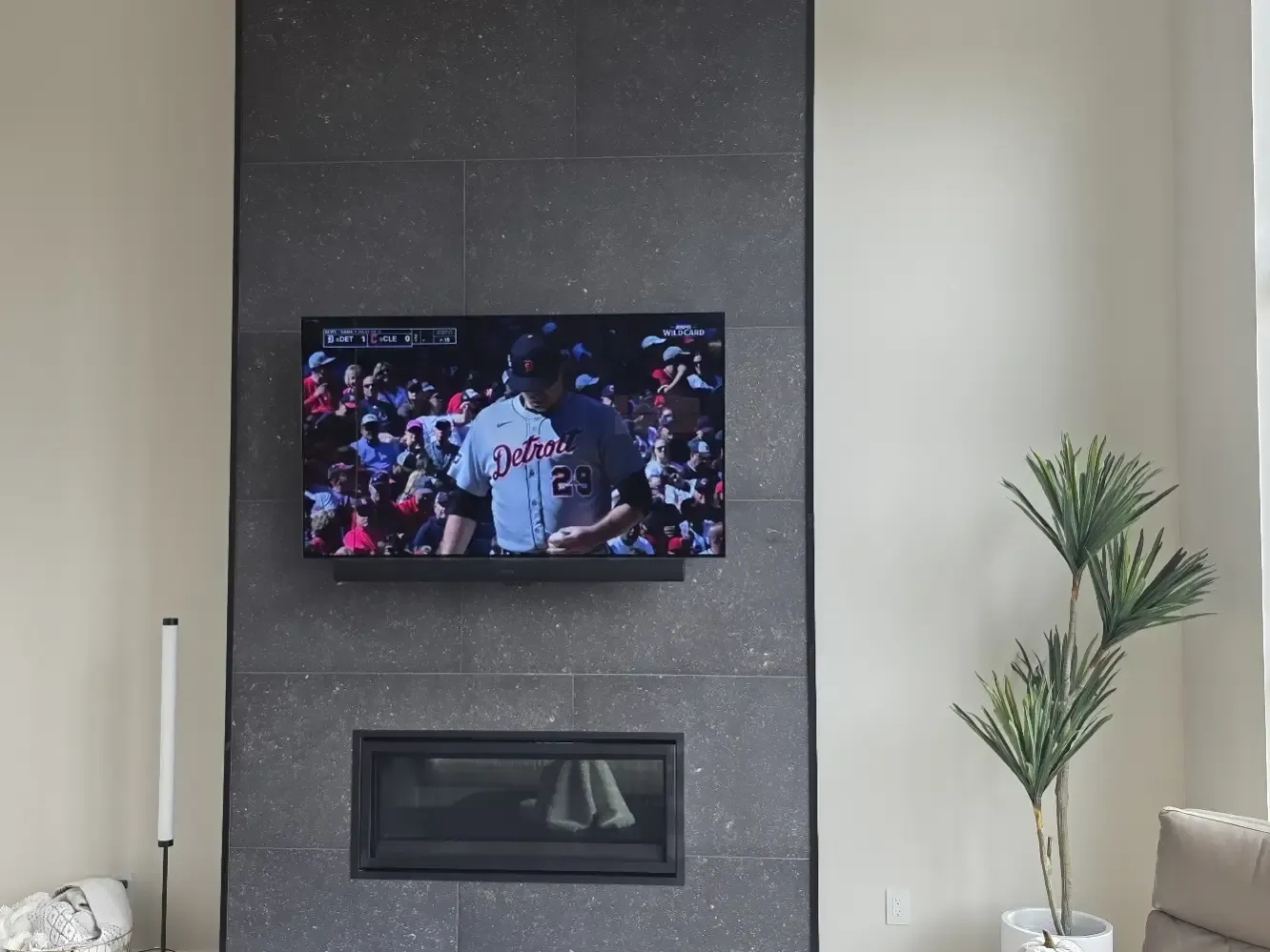 Wall-mounted flat screen TV above modern stone fireplace in living room