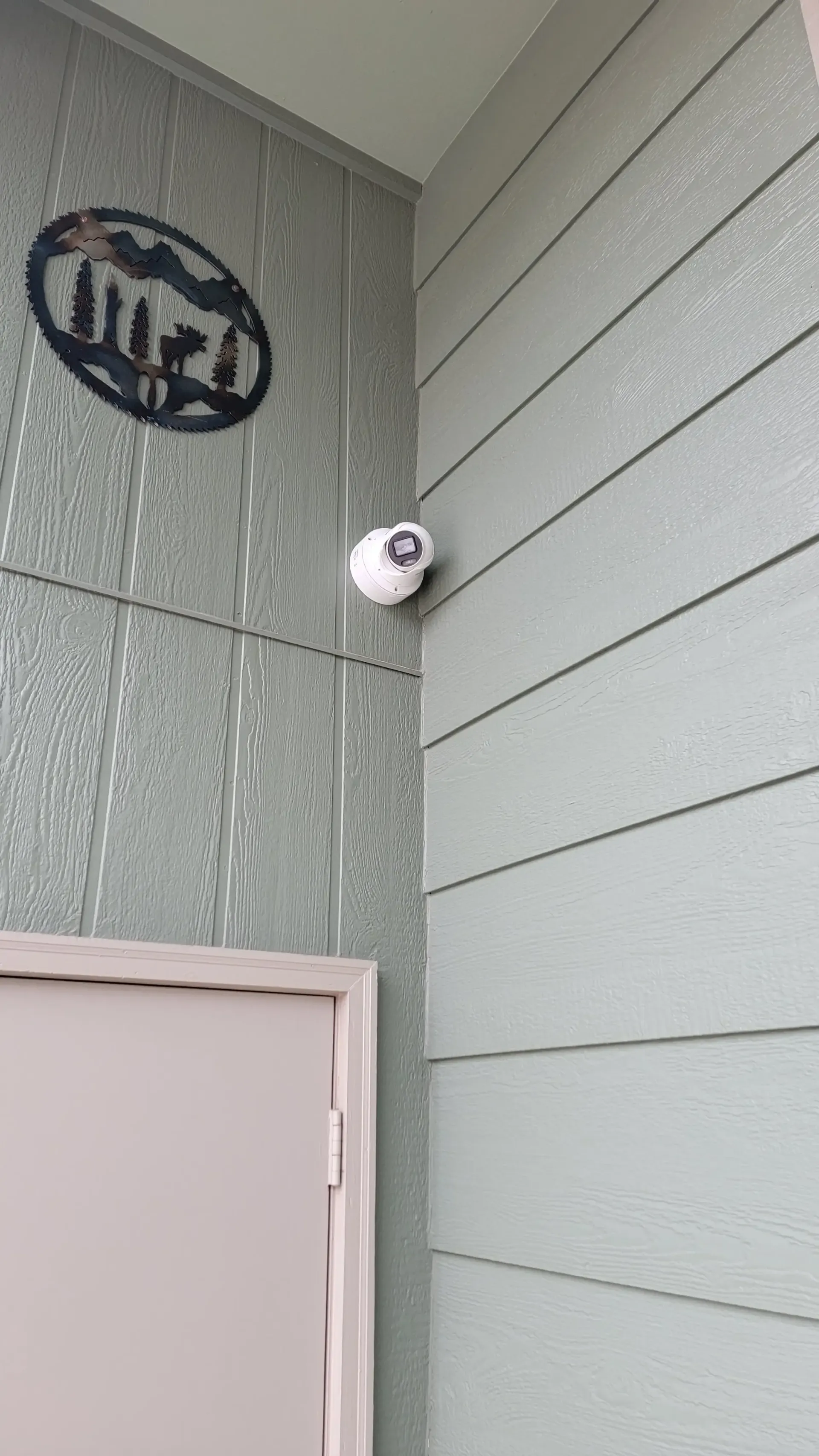 Outdoor security camera mounted on gray siding exterior wall of home