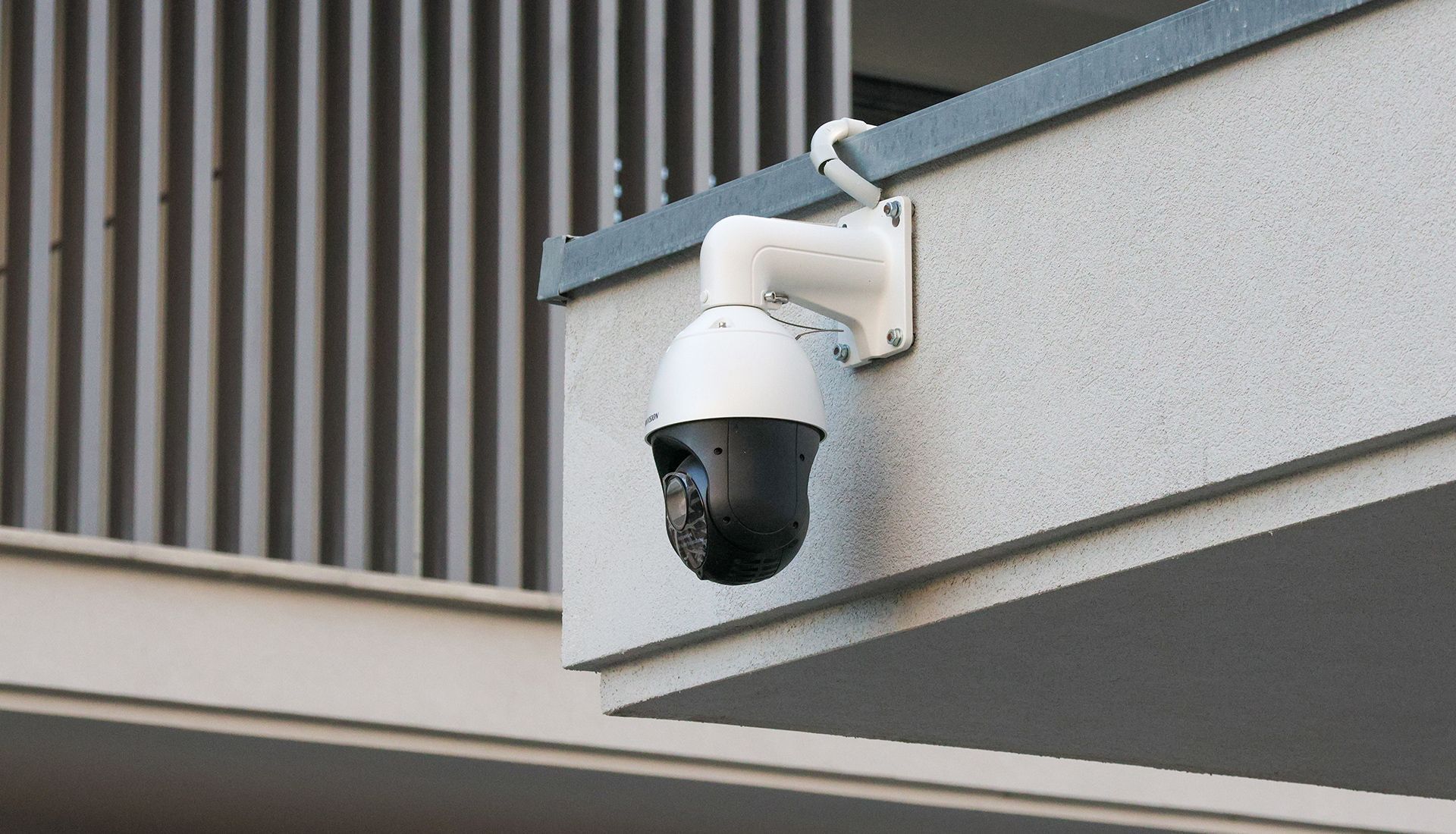 White security camera mounted on a building's exterior, angled down.