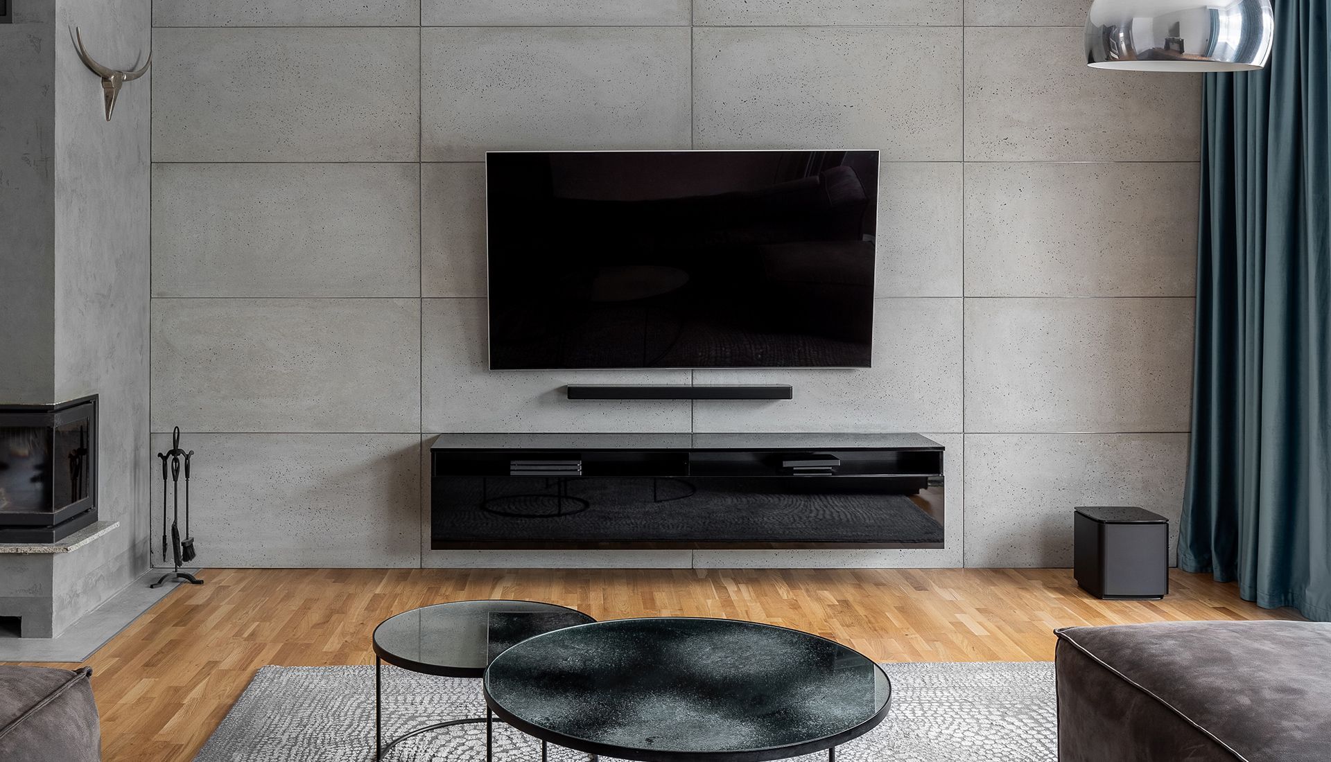 Living room with mounted TV, soundbar, and black floating cabinet against a concrete wall.