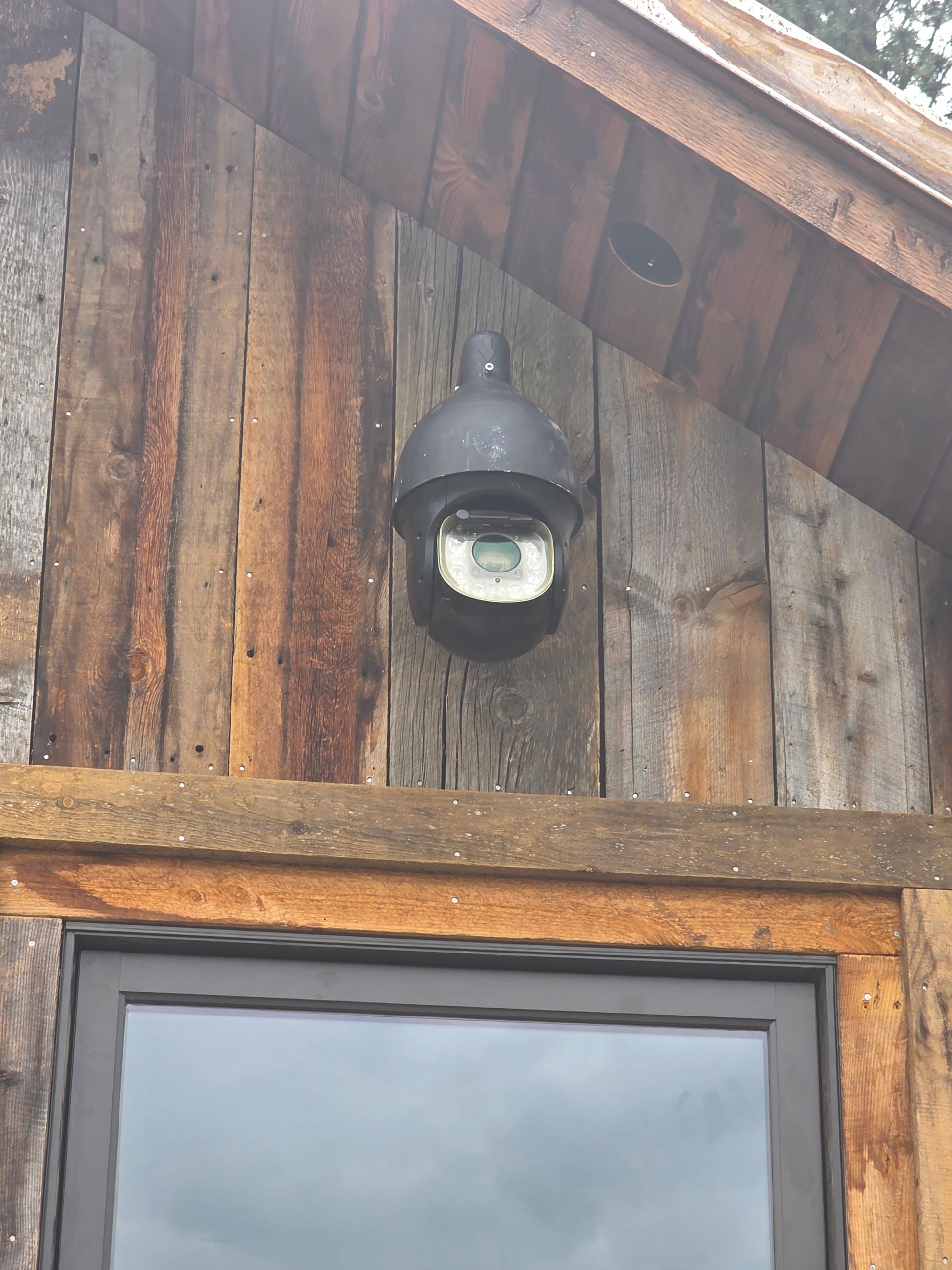 Outdoor PTZ surveillance camera mounted on log cabin in Hamilton, MT — security camera installation by Smart Home Solutions