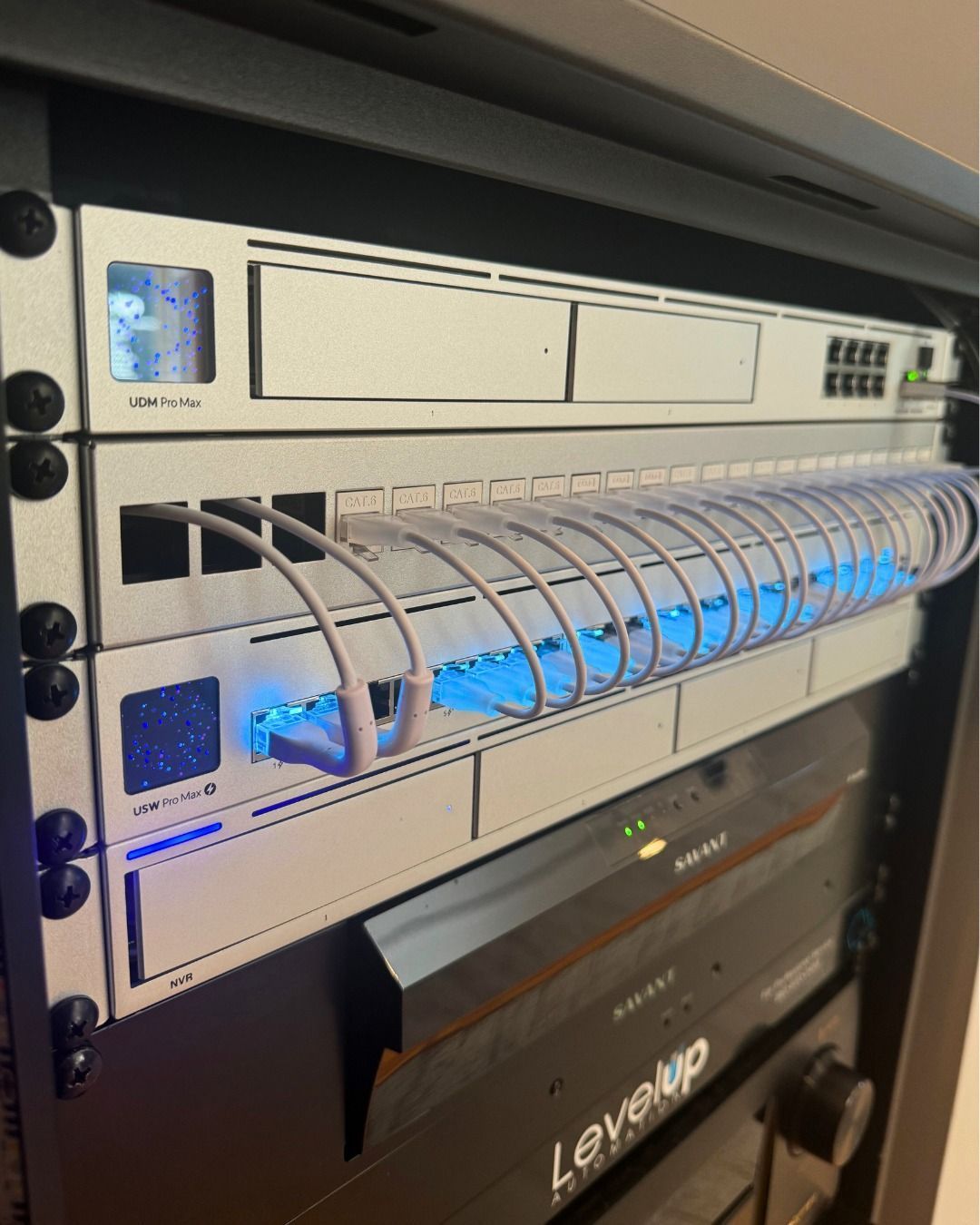 A server rack with several mounted electronic devices, featuring a blue-lit cable organizer.