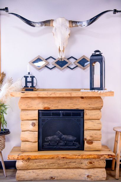 A wooden fireplace with a bull skull on the wall above it.