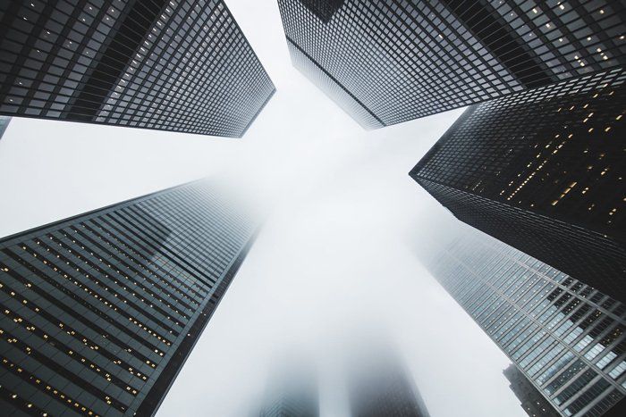 Looking up at a group of tall buildings with a white sky in the background