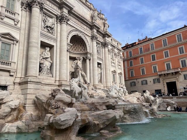 Trevi Fountain in Rome, Italy; Baroque architecture with statues, water cascading into a pool.