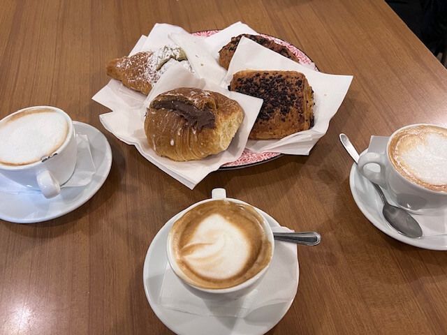 Two cups of coffee and a basket of pastries on a table