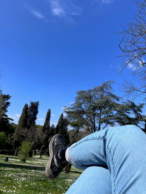 Person laying on the grass at Villa Borghese looking at the sky