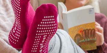 Woman wearing socks laying down on the bed reading book