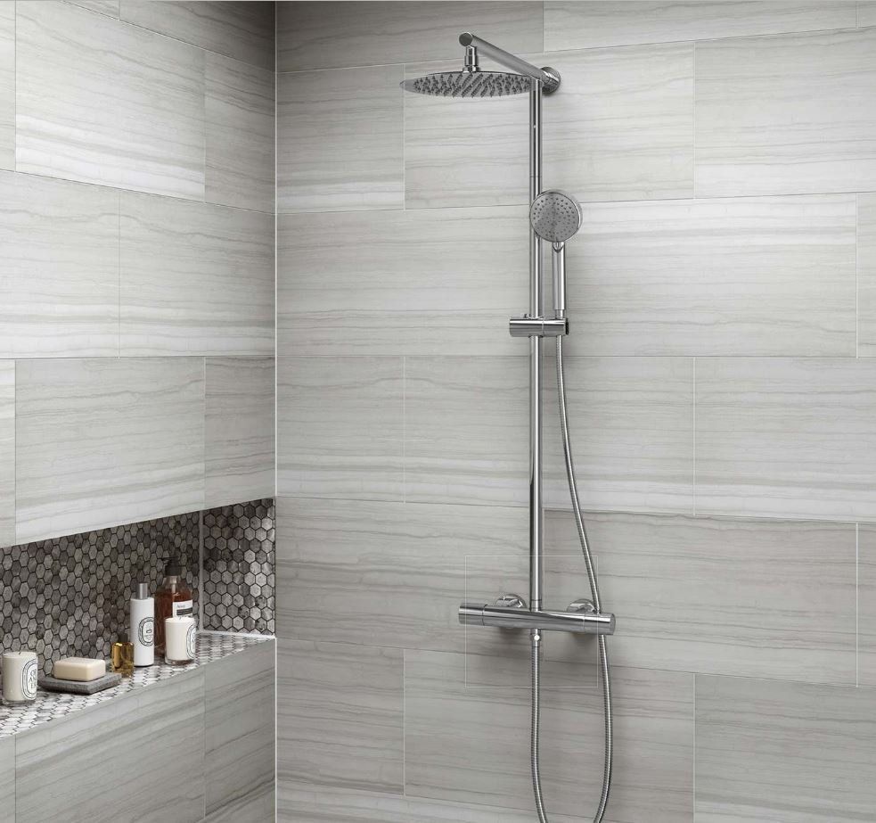 A bathroom with a shower head and a shelf with soaps on it.