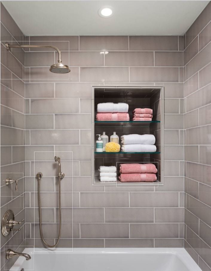 A bathroom with a tub , shower and a shelf filled with towels.