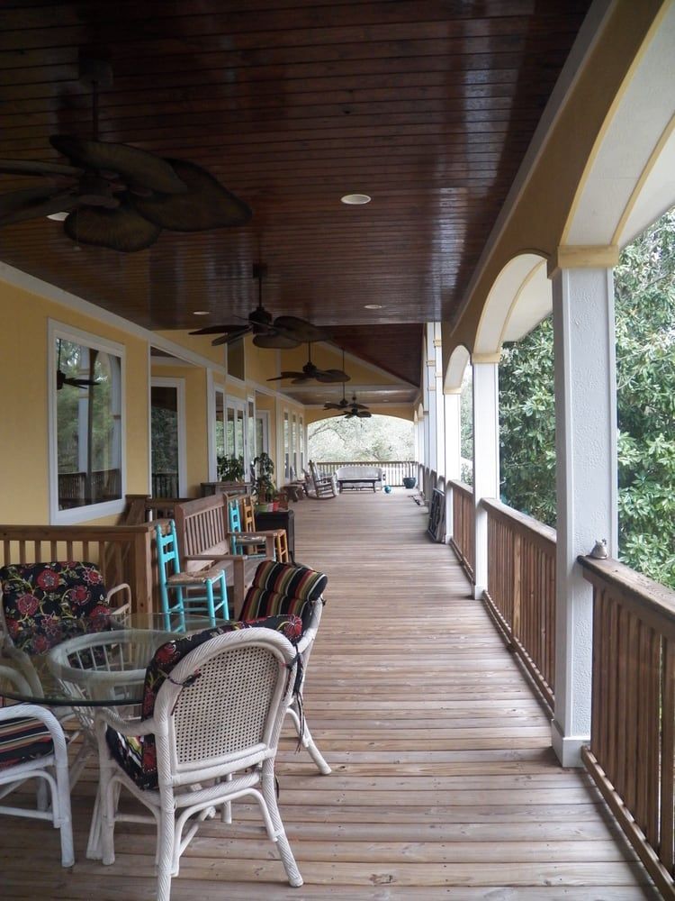 A long wooden porch with a table and chairs on it
