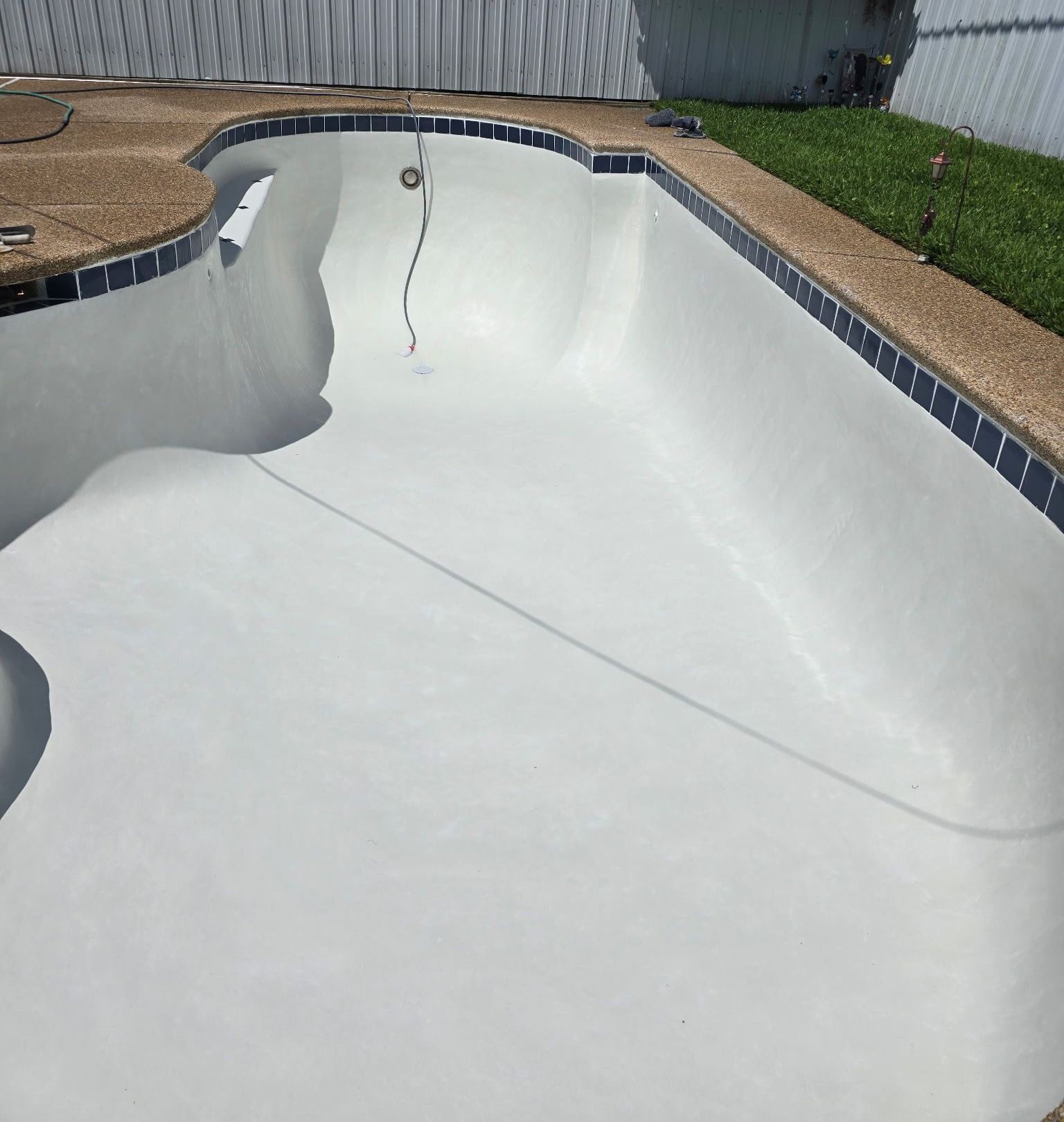 An empty swimming pool with a house in the background