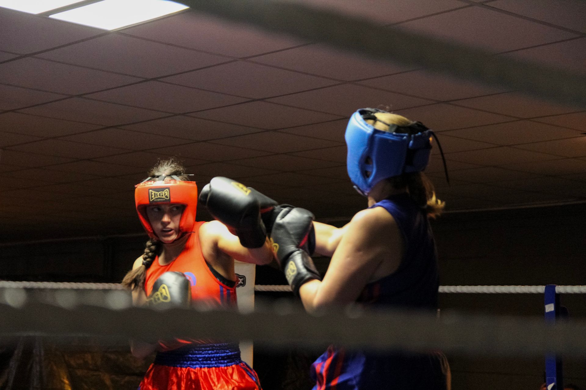 Two boxers sparring in a boxing ring, both wearing protective headgear and gloves.