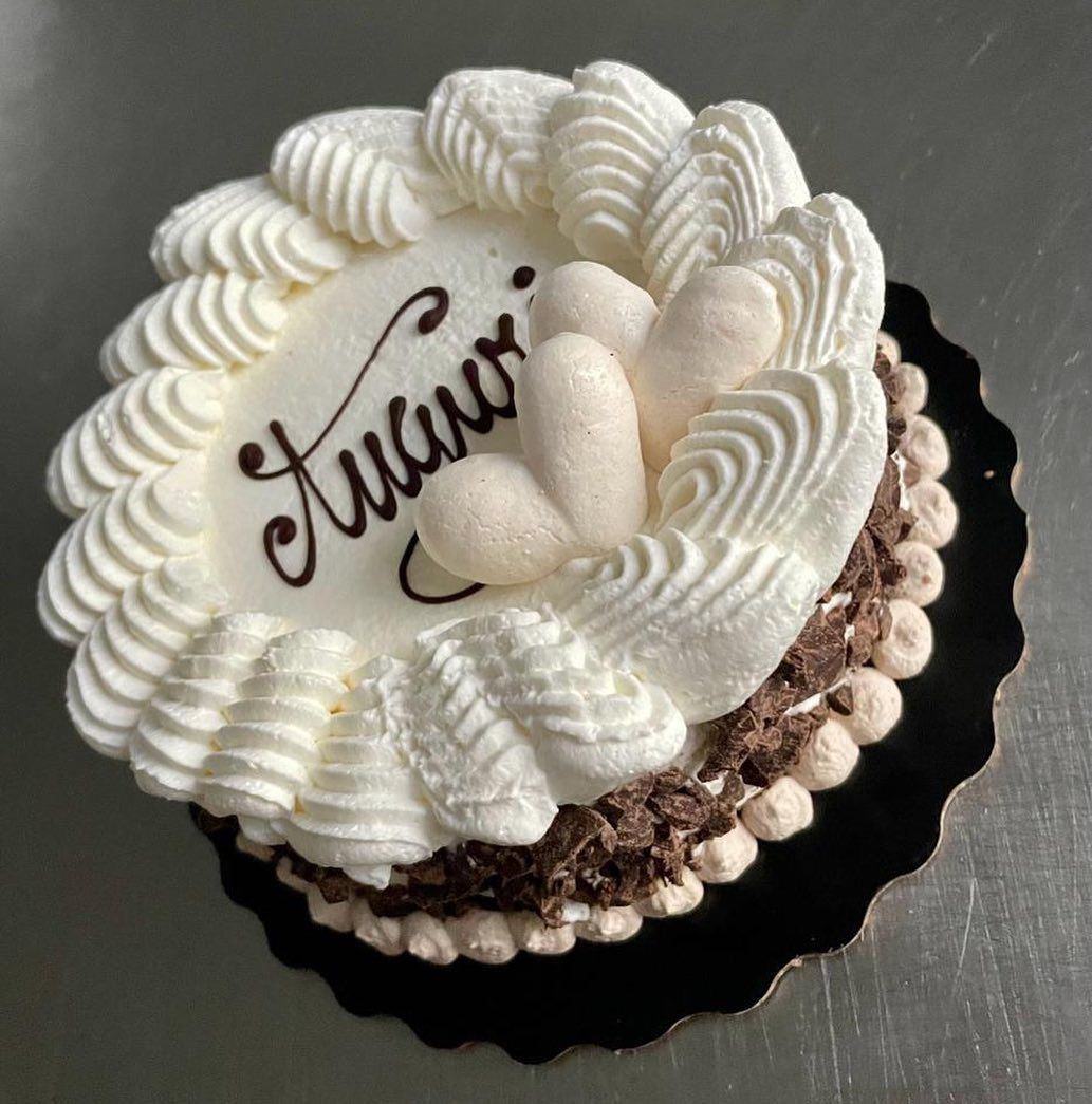 Piccola torta con glassa bianca, bordi di cioccolato e il nome 
