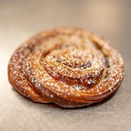 Una pasta sfoglia rotonda con un disegno a spirale, spolverata di zucchero a velo.