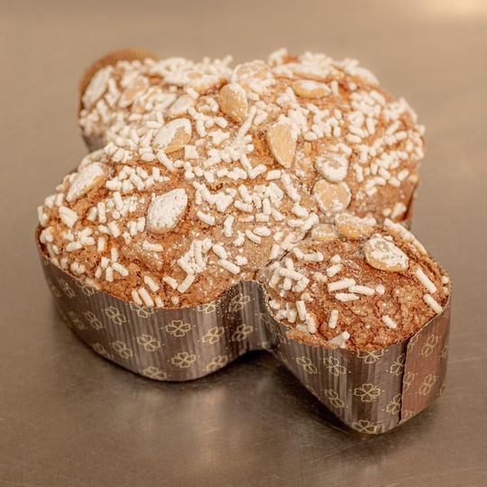 Una colomba a forma di uccello, con mandorle e granella di zucchero, su uno stampo di carta marrone a forma di fiore.