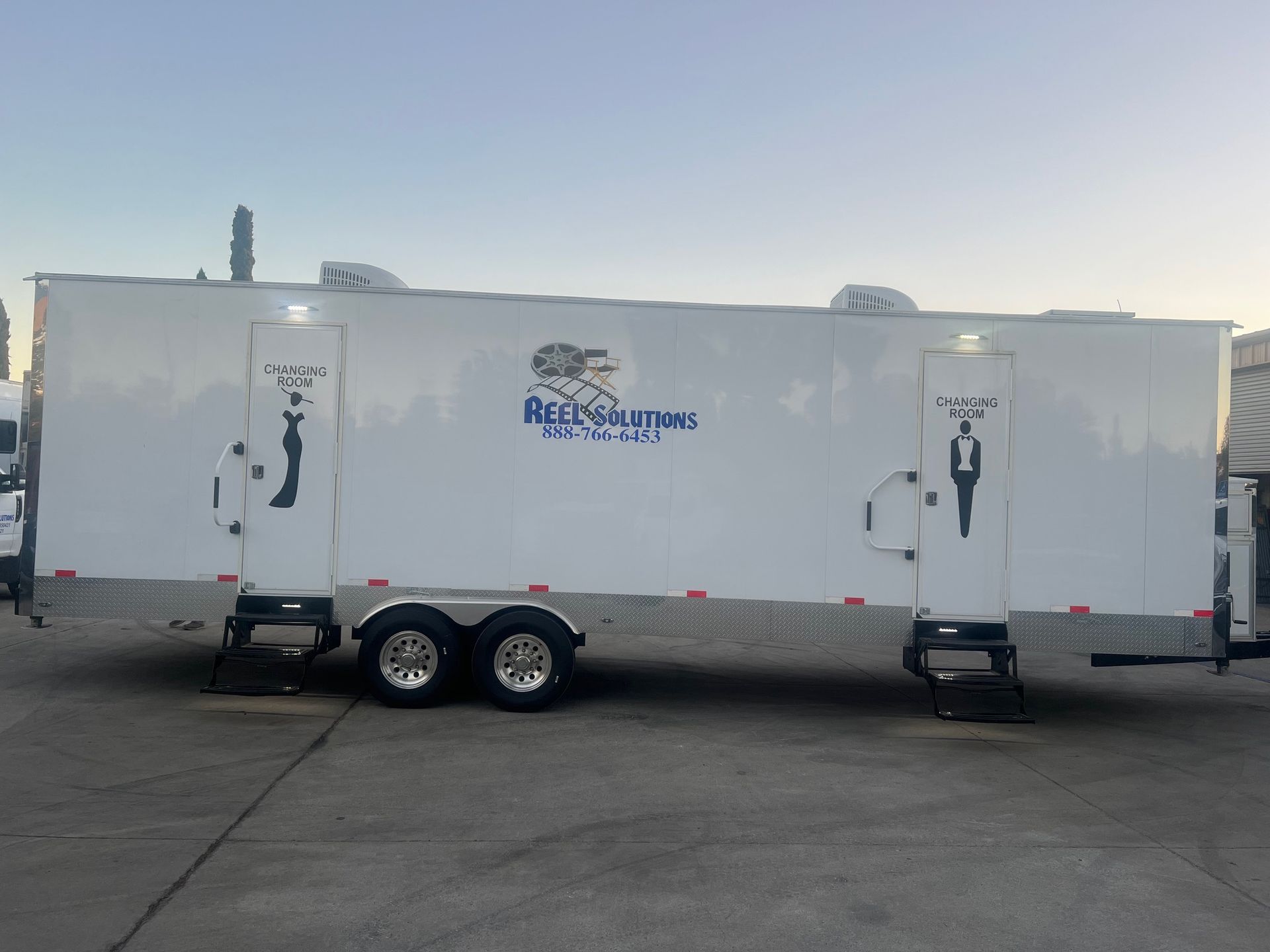 White portable restroom trailer with two entrances, the logo "Aqua Solutions".