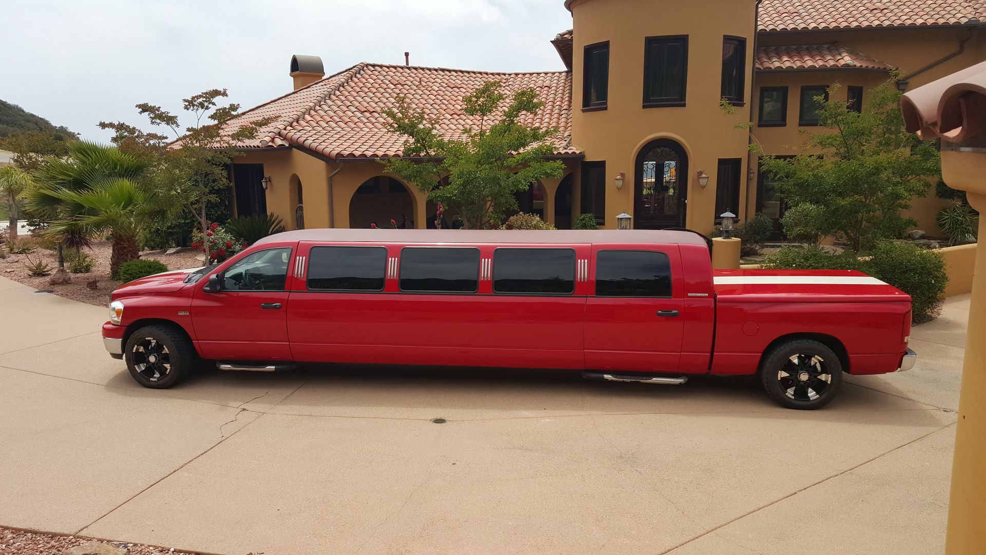 Red limousine truck parked on a driveway in front of a large house.