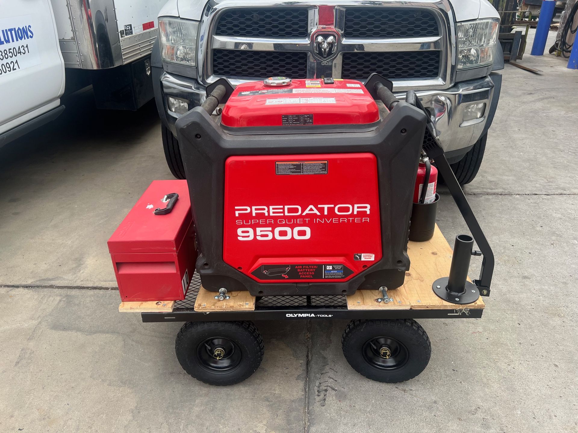 Red Predator 9500 generator on a cart, in front of a Dodge truck. A red toolbox and fire extinguisher are also present.