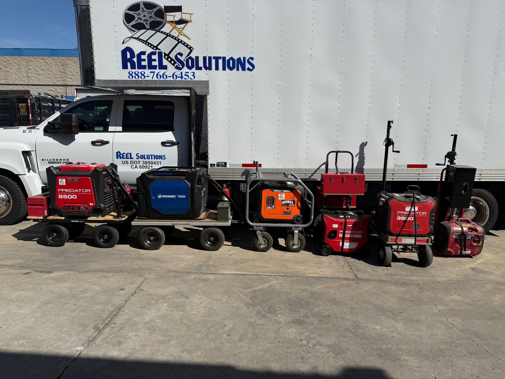 Several generators and equipment carts parked in front of a white truck with 