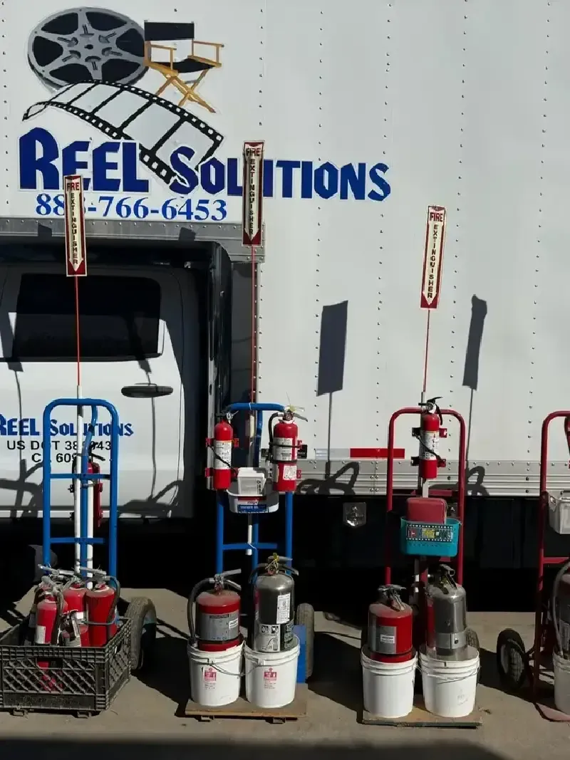 Reel Solutions truck with fire extinguishers on stands and carts, outdoors.