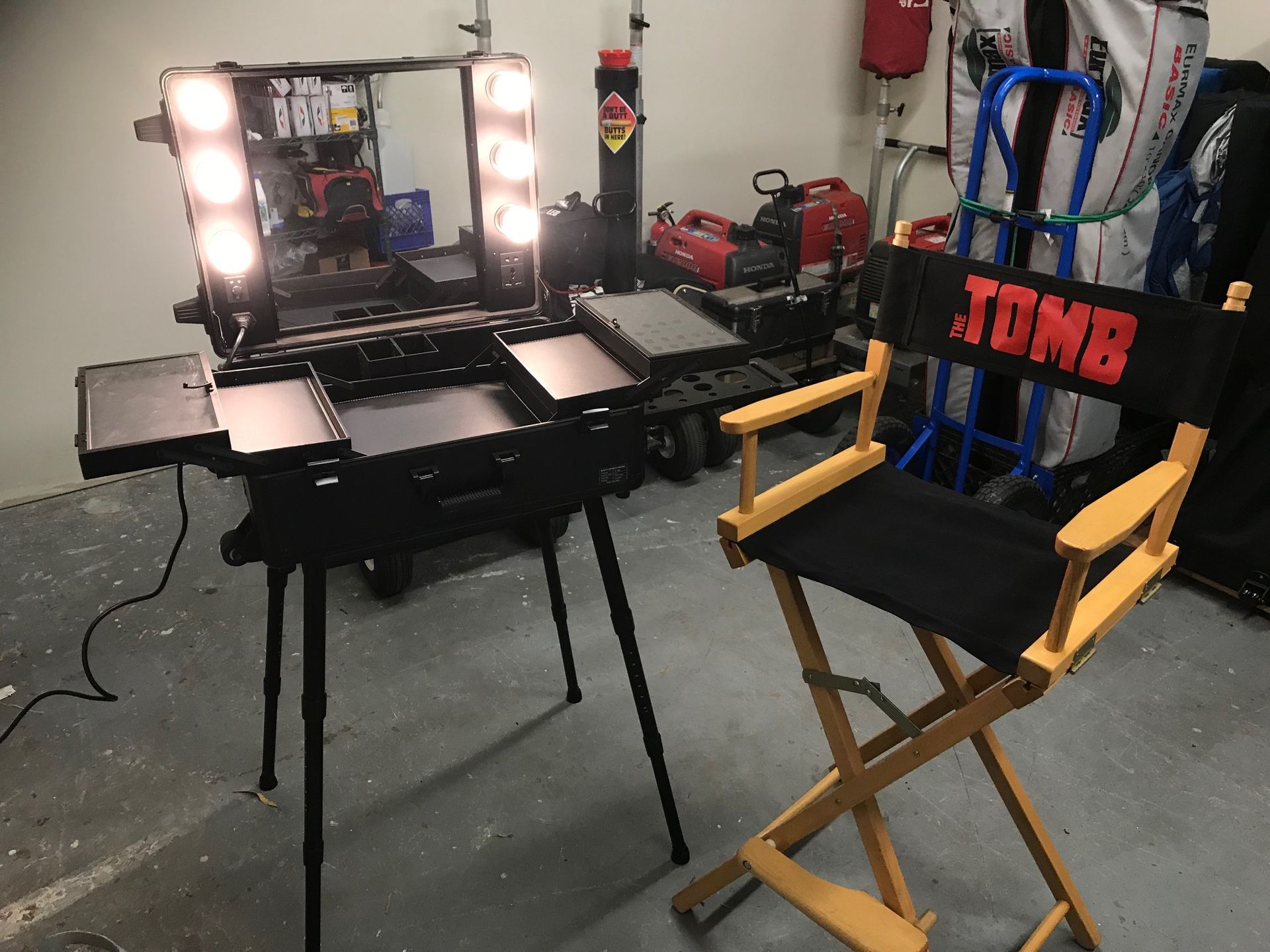 Makeup artist station with lit mirror, black case, director's chair with 