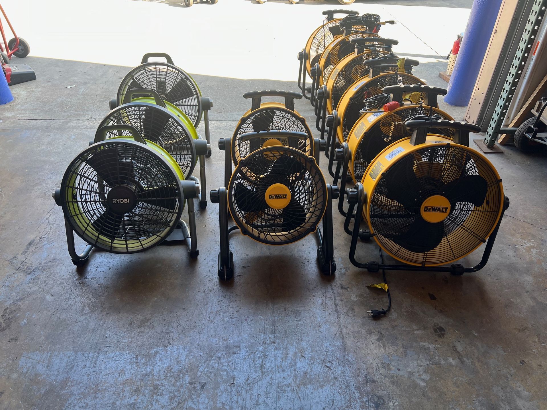Several black and yellow industrial fans lined up on concrete.