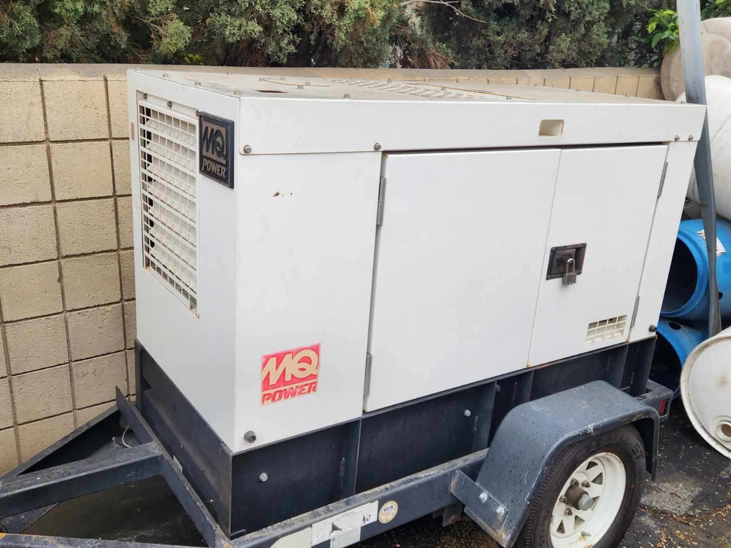 White and black generator on a trailer with MO Power logo in a yard.