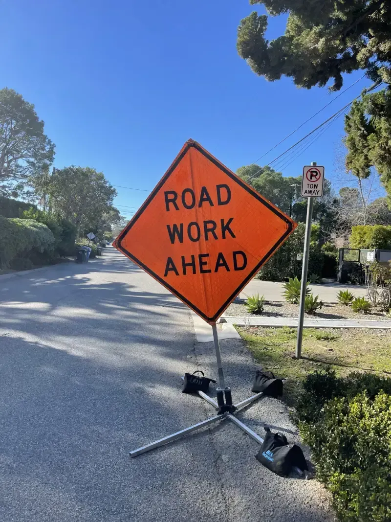 Orange road work sign on a street reads 