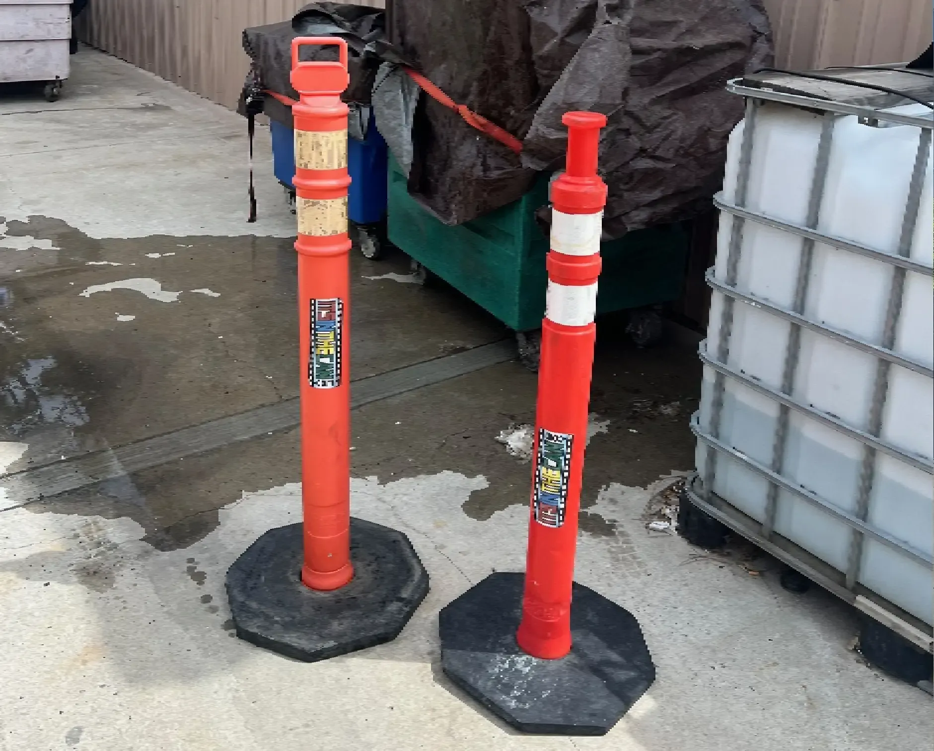 Two orange and white traffic cones on a concrete surface.