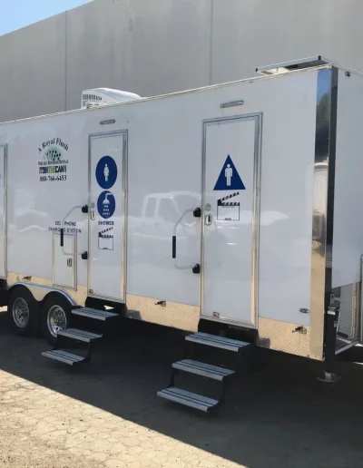 White portable restroom trailer with two separate entrances and stairs.
